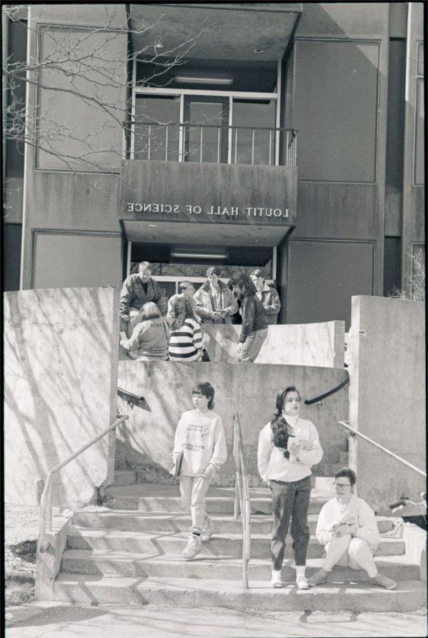 Students sit and stand in front of Loutit Hall of Science in a photo from 1991.