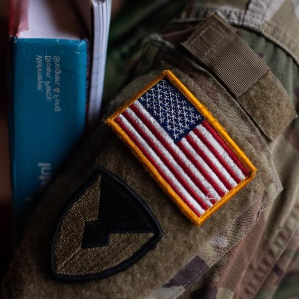 近距离显示美国国旗贴片的学生退伍军人的制服拿着书.