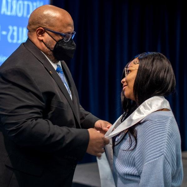 Dr. William Washington, TRIO program director, right, places a graduation stole on Brianna McKinney during the TRIO academic achievement ceremony at GVSU on April 15.