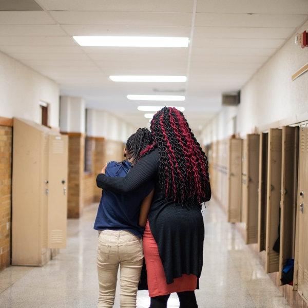 一位老师正在安慰走在学校走廊上的学生.